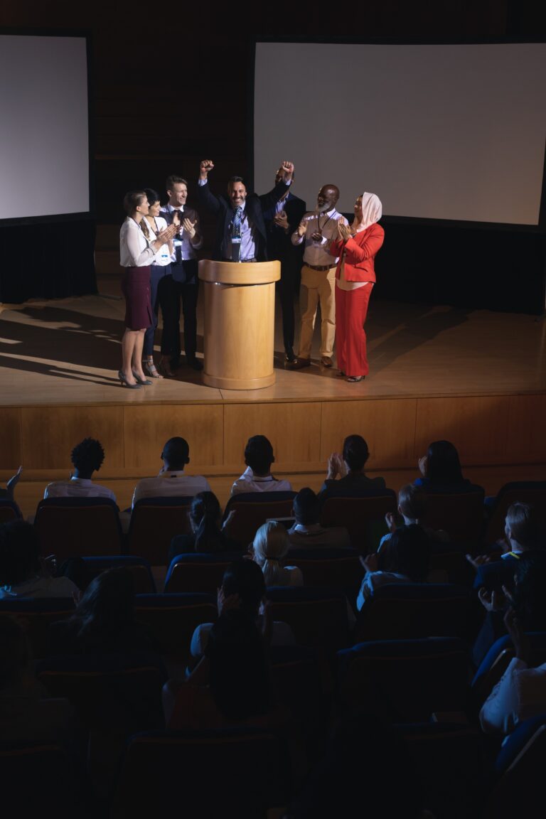 Happy businessman standing at the stage of the auditorium in front of audience